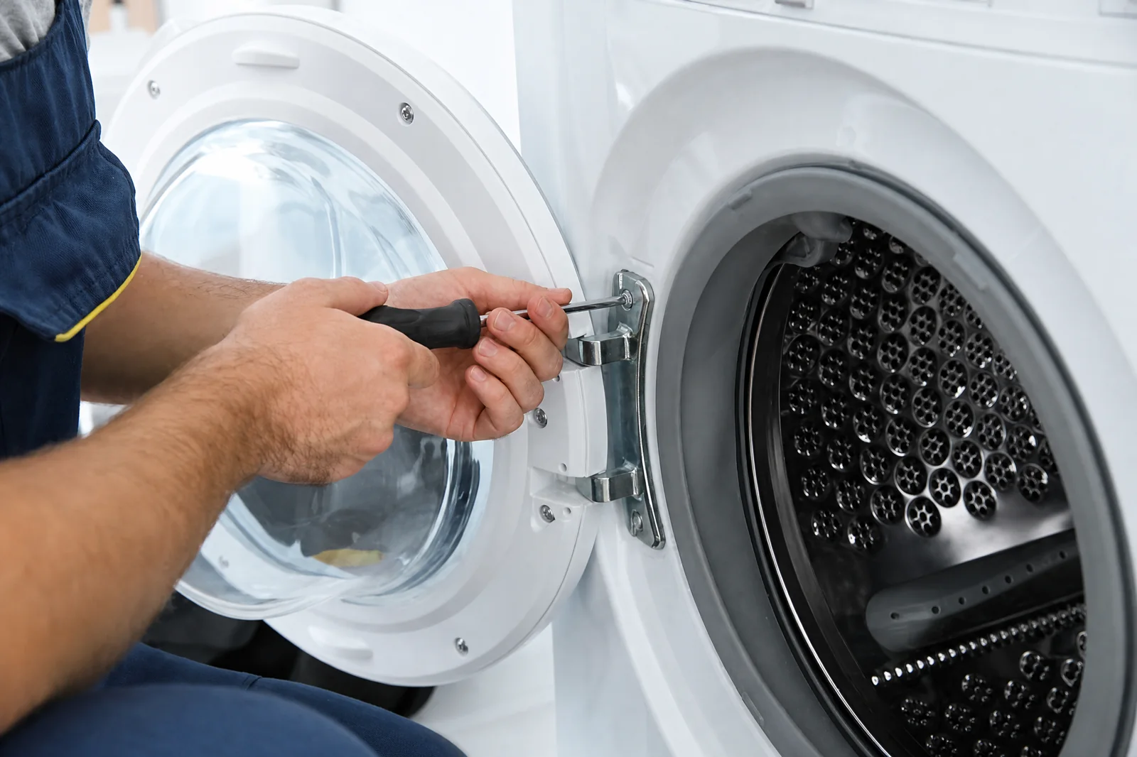 Technician troubleshooting a front-loading washing machine